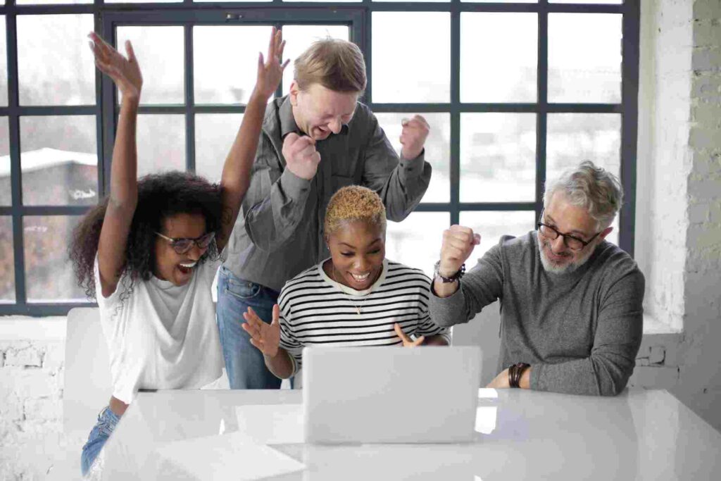 Groupe de collègues devant un ordinateur qui explose de joie devant ses performances SEO grâce à un maillage interne efficace
