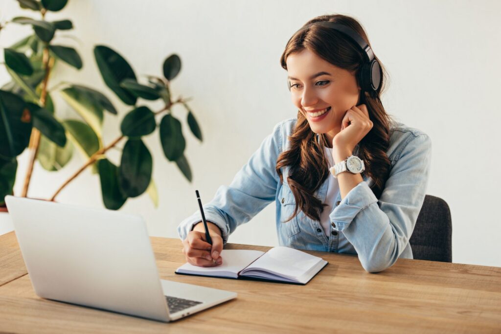 portrait d'une jeune femme souriante avec des écouteurs participant à un webinaire au bureau